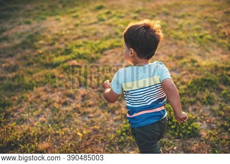 Upper View Photo Of A Caucasian Boy Playing And Running On A Field During A Summer Evening