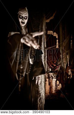 Halloween. Portrait of a cursed nun extending her hand forward, standing in the abandoned chapel. Horrors.