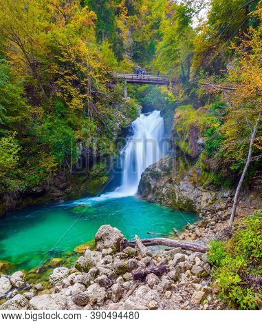 Picturesque old bridge over the Vintgar mountain gorge. Powerful rumbling waterfall on a mountain river. Slovenia. The concept of active and photo tourism