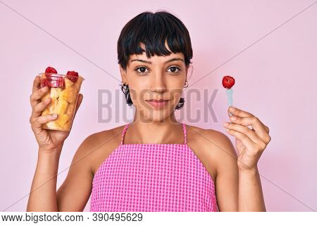 Beautiful brunettte woman eating fresh and healthy fruit relaxed with serious expression on face. simple and natural looking at the camera. 