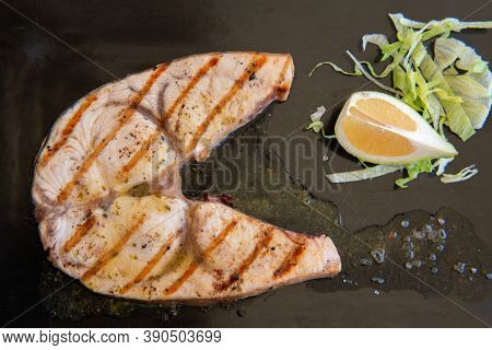 Cooked swordfish. Grilled slice of fish with lemon and salsd on plate in restaurant