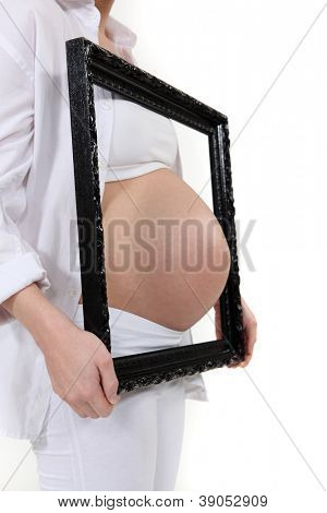 หญิงตั้งครรภ์ poking ท้องผ่านเฟรมรูปภาพ