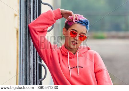 Portrait Of A Young Girl With Short Colorful Hair And Nose Piercing Satanding Near The Wall With Woo