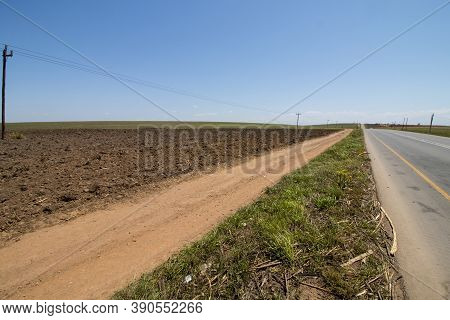 Dirt Farm Road And Plouged Field Running Next To District Road