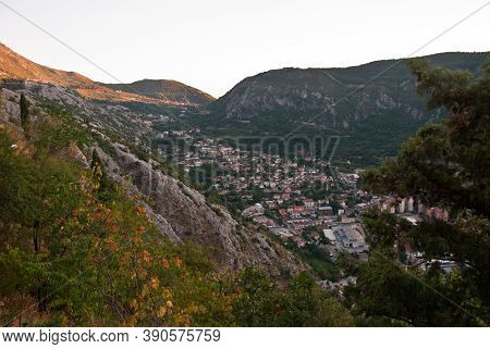 A Small Mediterranean Town With Low Houses With Tiled Roofs Nestled In A Valley Between The Mountain