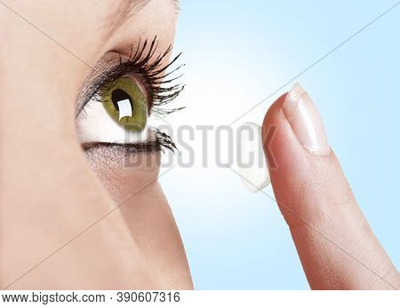 Closeup Of A Woman Inserting A Contact Lens In Her Eye In A Blue Background