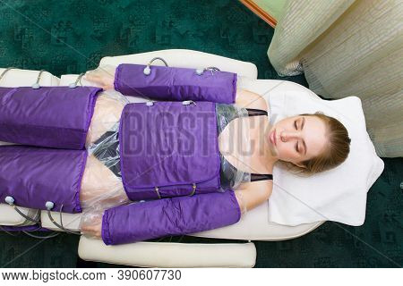 Young Beautiful Woman On Procedures In A Special Pressotherapy Suit In The Spa Salon. Treatment And 