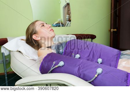 Young Beautiful Woman On Procedures In A Special Pressotherapy Suit In The Spa Salon. Treatment And 