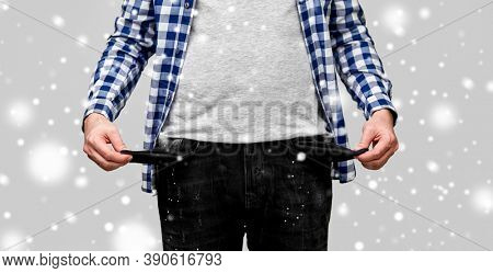 bankruptcy, financial crisis and poverty concept - close up of man showing empty pockets in winter over snow on grey background
