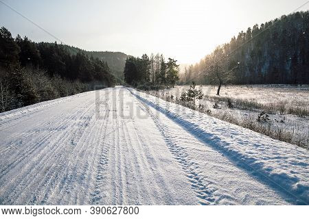 Tire Tracks In The Snow, Winter Road, Empty Road In Winter Goes Far To The Horizon, Covered With Sno