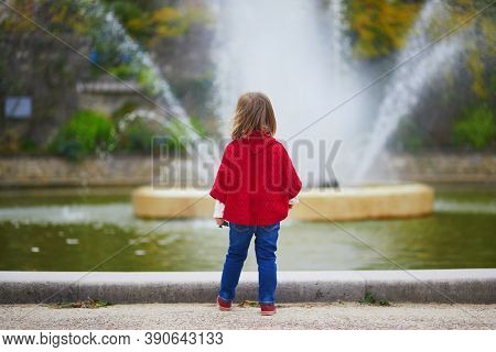 Adorable Toddler Girl In Red Poncho Walking In Autumn Park. Happy Kid Enjoying Fall Day In Paris, Fr