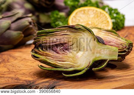 Fresh French Petit Violet Artichokes Heads Cultivted In Brittany, France With Lemon And Parsley