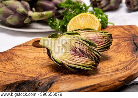 Fresh French Petit Violet Artichokes Heads Cultivted In Brittany, France With Lemon And Parsley