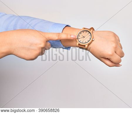 Hand of caucasian young businesswoman wearing wristwatch. Pointing with finger to watch over isolated white background