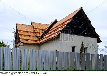 Unfinished Church With The Wooden Scaffolding In Under Construction, Metal Fence For Protection From