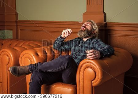 Confident Bearded Male Sit In Luxury Leather Armchair. Luxury And Success. Smoke Cigarette While Dri