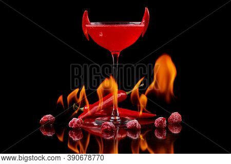 Red Cocktail With Raspberries And Searing Pepper On The Mirror With Flames Of Fire