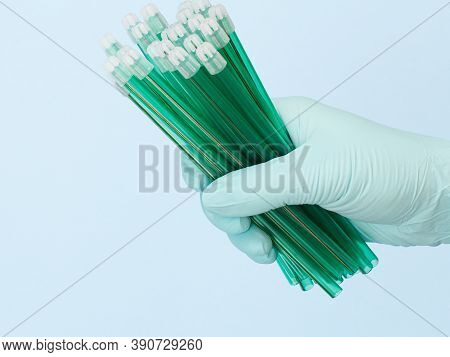 Dentist's Hand In A Latex Glove With Saliva Ejectors On The Blue Background. Medical Tools Concept.