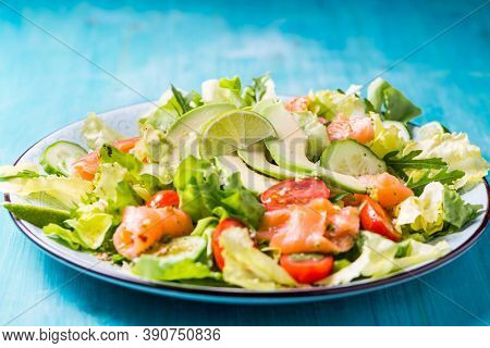 Healthy salad with smoked samlmon and avocado on cyan vackground