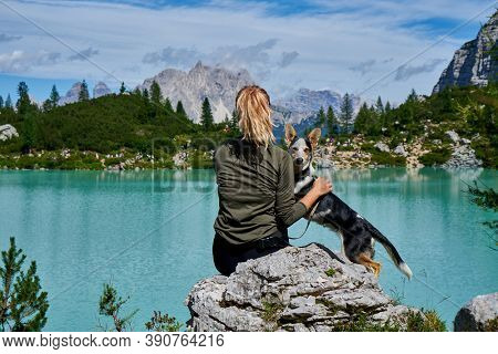                       a woman with a dog is resting on the shore of a mountain lake. vanlife         