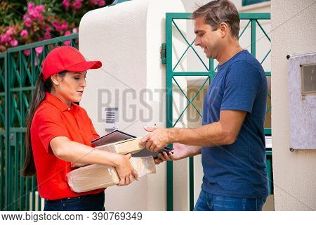 Caucasian Man Receiving His Order From Deliverywoman. Latin Courier Delivering Order, Holding Parcel