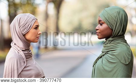Two Muslim Women Enemies Standing Separately Looking At Each Other With Cool Attitude Posing In Park