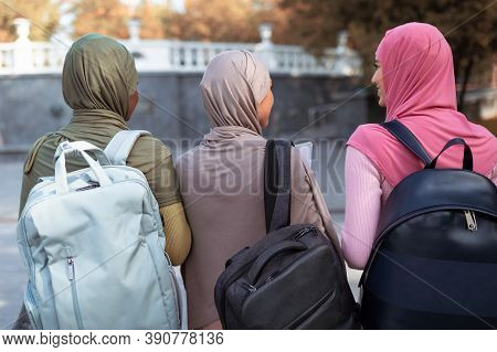 Three Unrecognizable Muslim Students Ladies With Backpacks Walking Back To Camera In Park Outdoor. U