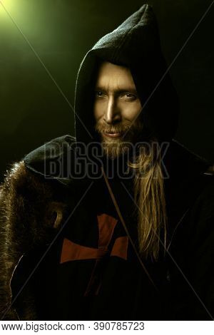 Portrait of a medieval pilgrim in old historical clothes over black background. Historical reenactment. Copy space.