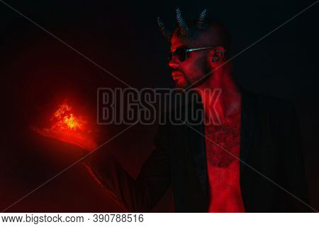 A portrait of a bad demon in sunglasses with fire in hand. Horror movie, nightmare. Halloween.