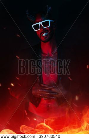 A portrait of a bad demon with sunglasses in fire. Horror movie, nightmare. Halloween.
