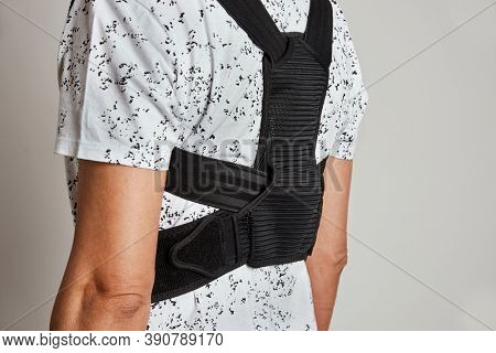 closeup of a young caucasian man wearing an upper back posture corrector as is standing