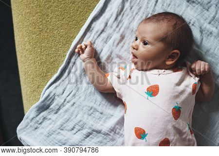 Lovely Caucasian Newborn Girl Is Looking At Her Parents With Opened Mouth Lying On A Quilt