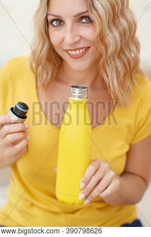 Young Woman In Yellow T-shirt Holding Yellow Reusable Bottle