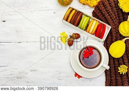 French Macarons In Autumn Colors With Cup Of Hot Tea