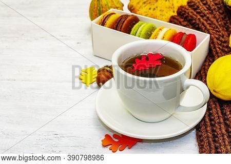 French Macarons In Autumn Colors With Cup Of Hot Tea