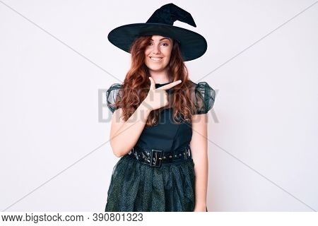 Young beautiful woman wearing witch halloween costume cheerful with a smile on face pointing with hand and finger up to the side with happy and natural expression 