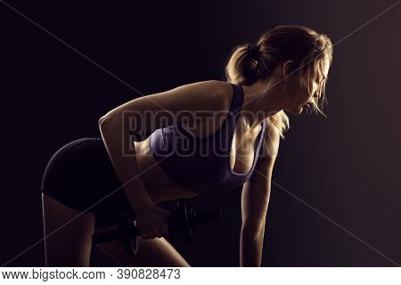 Slim Athletic Woman Holding Dumbbell In The Hand On Black