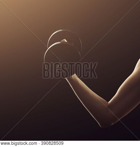 Slim Athletic Woman Holding Dumbbell In The Hand On Black