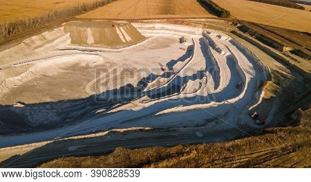 Opencast mining quarry with machinery at work - Aerial view. Industrial Extraction of lime, chalk, calx, caol