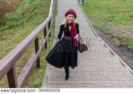 Happy Walks Up The Stairs And In A Burgundy Palette And Biret, An Adult In Black Clothes, In The Fal