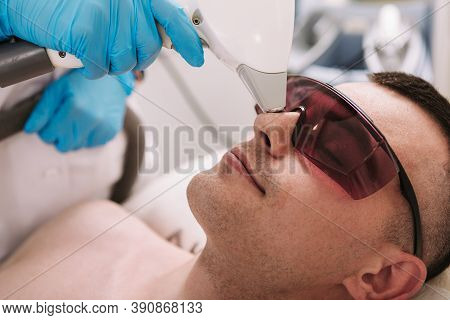 Cropped Close Up Of A Young Man Removing Hair On His Nose At Beauty Salon. Professional Comsetologis