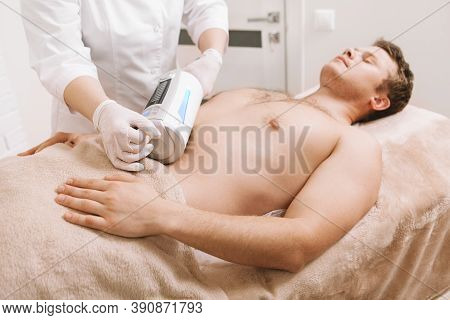 Male Client Relaxing While Professional Therapist Using Endospheres Massaging Device On His Stomach