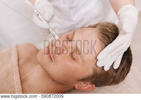 Close Up Of A Relaxed Male Client Receiving Facial Skincare Treatment By Cosmetologist At Beauty Sal