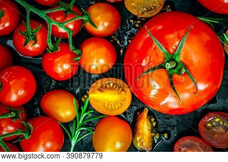 Variety of tomatoes, top view, over black.  Beef tomato, cherry tomatoes, roma and truss, whole and cut.