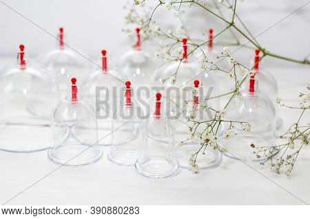 Jars For Hijama On A White Wooden Background And White Flowers. Bloodletting. Sunnah Treatment. Isla