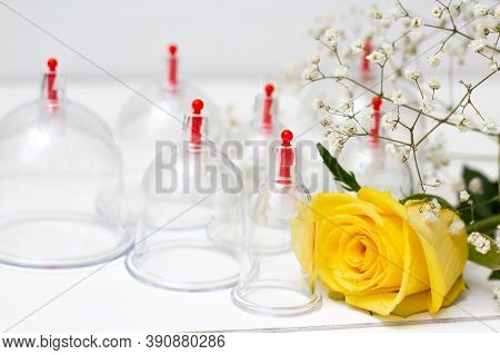 Jars For Hijama On A White Wooden Background And Yellow Flowers. Bloodletting. Sunnah Treatment. Isl