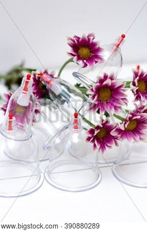Jars For Hijama On A White Wooden Background And Pink Harezantems. Bloodletting. Sunnah Treatment. I