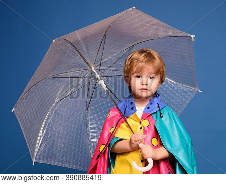 Smiling Little Boy Playing With Leaves And Looking At Camera. Cheerful Boy In Raincoat With Colorful