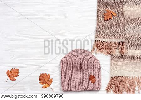 Autumn Flat Lay With Warm Woolen Scarf And Knitted Cap. Fashion Autumn Clothes On White Wooden Desk.