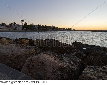 View Of The Sea And Stones On The Pedregalejo Beach At Dusk.